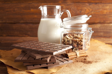 Chocolate, jug of milk, cinnamon, cocoa and mixed nuts in a jar