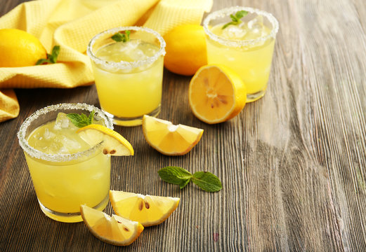 Glasses of lemon juice on wooden table, closeup