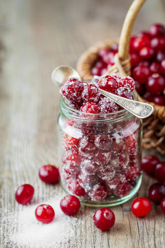 Cranberries with sugar in glass jar and basket with berries 