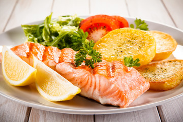 Fried salmon and vegetables on white background