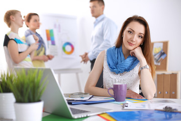 Portrait of attractive female  designer sitting on desk  in office
