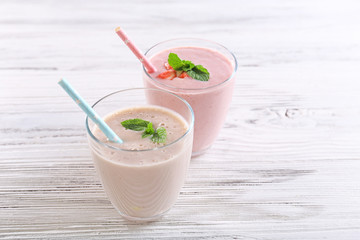 Fresh milk and strawberry yogurt on light wooden background