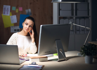 Young woman working in office, sitting at desk and talk on the phone