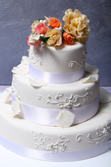 Wedding cake decorated with flowers on grey background