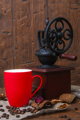 Red cup and grinder on wooden background