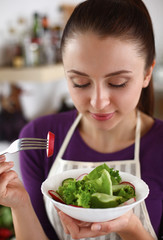 Young woman eating fresh salad in modern kitchen