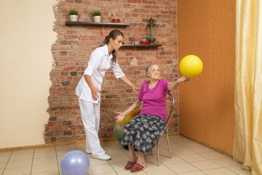 Senior Woman Sitting On A Chair And Holding Spiky Ball During Physiotherapy