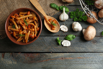 Delicious marinated mushrooms in bowl on wooden background