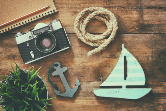 top view image of blank notebook, wooden sailboat, nautical rope and camera. travel and adventure concept. retro filtered image
