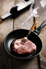 Marbled beef steak and wine bottle on wooden background