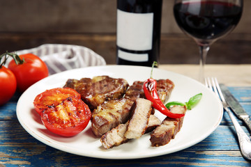 Roasted beef fillet and grilled vegetables on plate, on wooden background