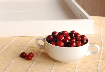 Fresh cranberries in glass bowl on kitchen background. 