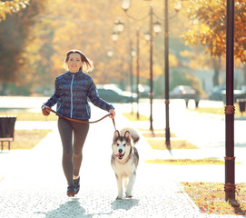Happy young woman jogging with her dog in park