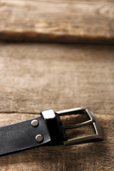 Leather belt with buckle on wooden background