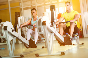 Fit  couple on row machine in gym