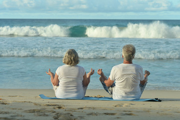 Fototapeta premium elderly couple meditate on beach