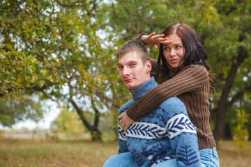 girl sitting on the back of a guy. A couple in love in the park