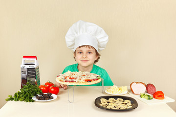 Little funny chef in chefs hat preparing a pizza