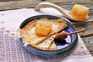 Pancakes with honey, comb in ceramic  blue plate on wooden 