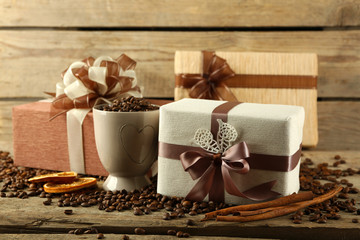 Beautiful gifts with bows and coffee grains on wooden background