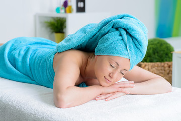 Obraz na płótnie Canvas beautiful woman wrapped in blue towel in massage salon
