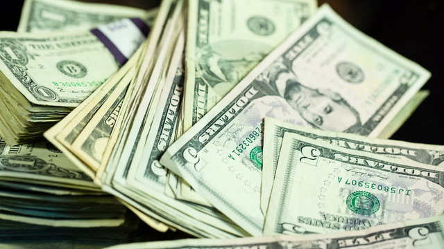 Cash Falls Loosely. 2 clips of cash falling onto table, some money in stacks and some loose.
