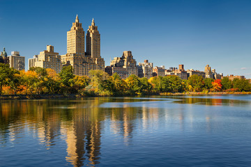 Central Park and Manhattan, Upper West Side with colorful Fall foliage. A clear blue sky and buildings of Central Park West reflecting in the Jacqueline Kennedy Onassis Reservoir. New York City.