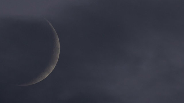 Crescent moon through mystical night sky with clouds