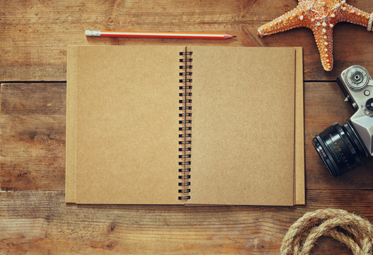 top view image of open blank notebook, nautical rope, starfish and camera. travel and adventure concept. retro filtered image
