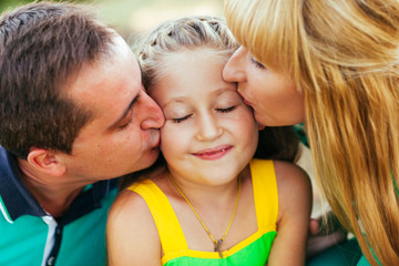 Fototapeta premium Young and beautiful family in the park. Mother, father and daugh