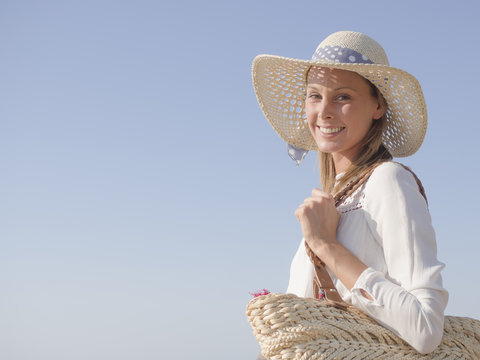 happy fashion blonde girl smiling portrait with soft blue background, wearing hat and a bag, profile photo
