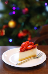 Fresh strawberry cheesecake. Selective Focus on the front upper edge of cake. Christmas tree in background