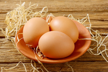 Three brown eggs on terracotta plate
