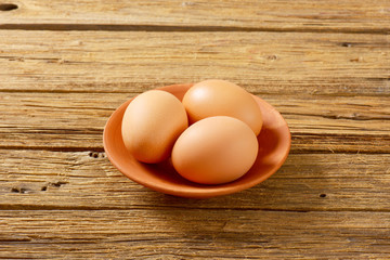 Three brown eggs on terracotta plate
