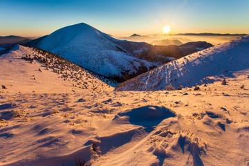 Beautiful winter landscape with snow patterns, peak and a rising sun.
