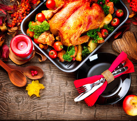 Thanksgiving dinner table served with turkey, decorated with bright autumn leaves