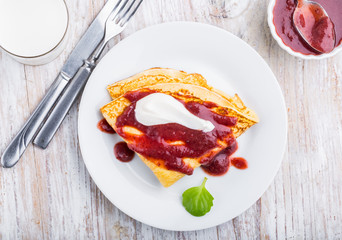 Pancakes with cottage cheese topped with strawberry jam and cream