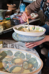 Work table of a pottery decorator of Caltagirone with different color containers and paintbrushes