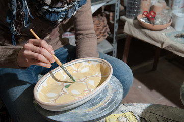 Pottery decorator from Caltagirone while finishing a ceramic tray in her work space