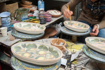 Work table of a pottery decorator of Caltagirone with different color containers and paintbrushes