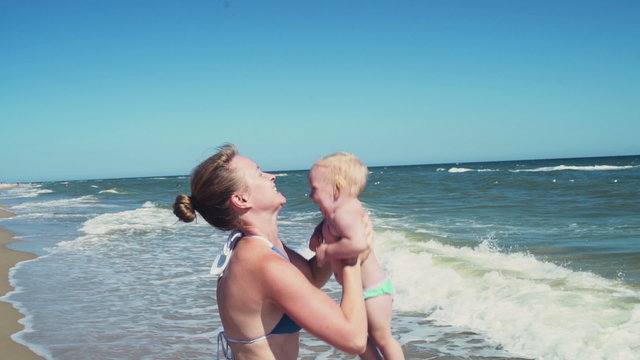 mother throwing up her child on the beach slow motion