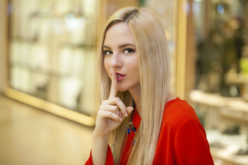 Portrait of attractive young blonde woman with finger on lips