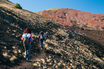 Group of young hikers walking on a trail leading to the north side of Mount Etna - obrazy, fototapety, plakaty