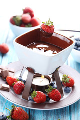 Chocolate fondue with fresh berries on a blue wooden table