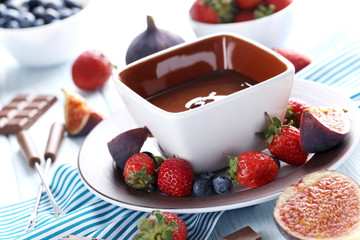 Chocolate fondue with fresh berries on a blue wooden table