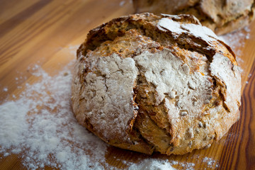 Round bread on the wooden table with flour around