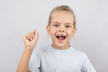 Girl holds the tooth in his hand and his mouth open showing a hole between the teeth