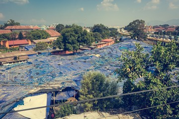 Local market covered with blue plastic sheets and tyres.