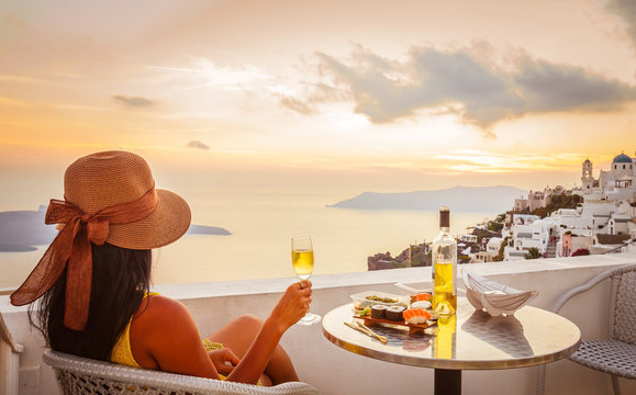 Fototapeta Female tourist enjoying food, wine and sunset view at Santorini, Greece