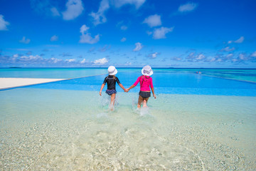 Adorable little girls in outdoor swimming pool on summer vacation